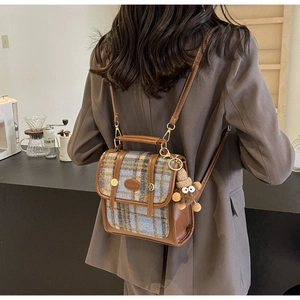 Detailansicht eines Vintage-Rucksacks mit blauem Karomuster und Bären-Anhänger