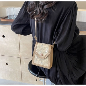 Détail d'un mini sac bandoulière en paille beige avec broderies et finitions cuir
