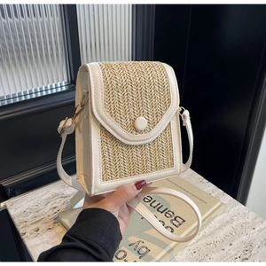 Detail of straw woven crossbody bag with white leather trim and gold metal hook
