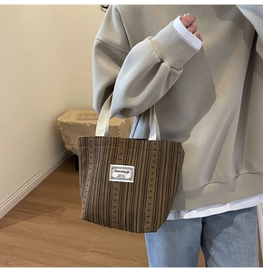 Detail of dark brown corduroy tote bag with woven label and cream sturdy handles