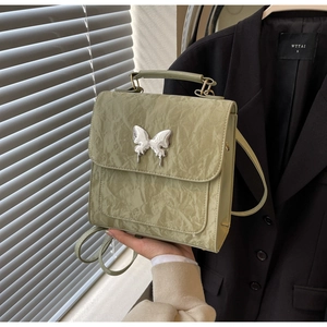 Détail du sac à main vert clair froissé avec une grande boucle papillon en métal argenté