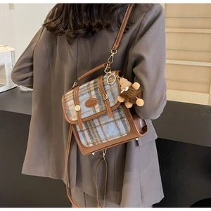 Detailansicht einer karierten Patchwork-Umhängetasche mit Bärenanhänger an einem Model