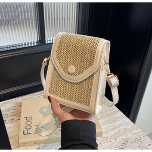 Detail of the woven straw pattern and synthetic leather trim on this beige crossbody bag