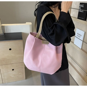 Detail of pink tote bag with FASHION metal tag and leather handles shown on shoulder