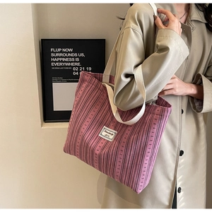 Detail of pink corduroy tote bag featuring woven texture and white logo label
