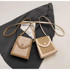 Detail of hand-woven straw crossbody bags in khaki and cream with leather accents