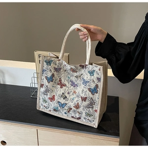 Gros plan sur la broderie papillon de ce sac cabas vintage en toile beige robuste