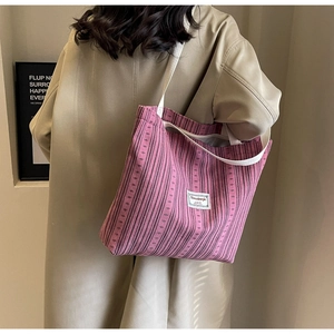 Detail of mauve corduroy tote bag with vertical stripes on a model in trench coat