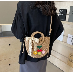 Detail of handmade straw crossbody bag with crochet flowers and white lace bow