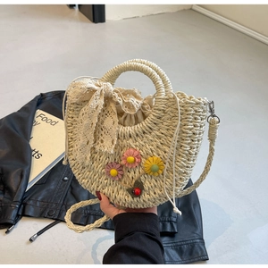 Detail of hand-woven straw bag with floral accents and a large lace bow decoration