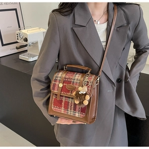 Detail der Vintage-Karo-Handtasche mit Lederbesatz und süßem Plüschbär-Anhänger