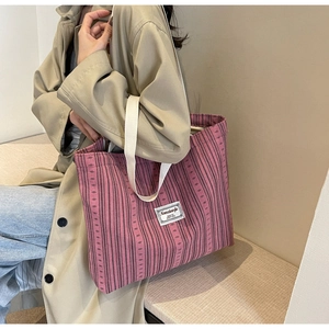 Detailed side view of large corduroy tote bag in purple with white woven handle