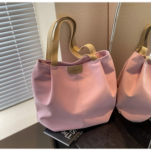 Detail of pink nylon tote bag with fashion leather tag and khaki woven handles