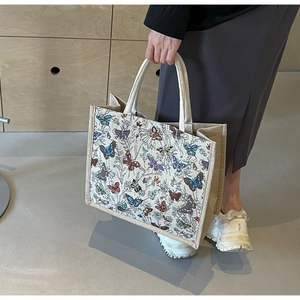 Détail d'un sac cabas en toile avec broderies de papillons colorés et doubles poignées