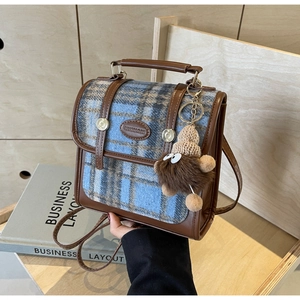 Detail eines Karo-Rucksacks mit Lederbesatz und süßem Monster-Schlüsselanhänger