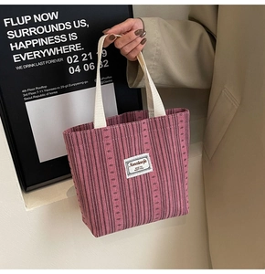 Close-up of pink striped tote bag featuring a white square patch with brand lettering