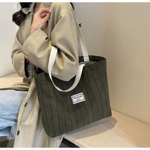 Close-up of dark green corduroy tote bag with white woven straps and minimal label tag
