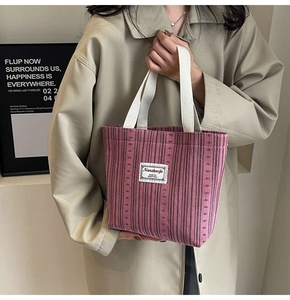 Detailed close-up of pink striped corduroy tote bag with cotton handles and brand label