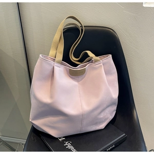 Detail of the pink nylon tote bag with fashion label and khaki woven straps on a chair
