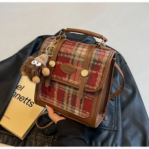 Detail der Vintage-Tasche mit Karomuster, Lederbesatz und Plüschmonster-Anhänger