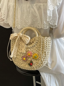 Handwoven beige straw basket bag with 3D floral accents and a stylish lace bow detail