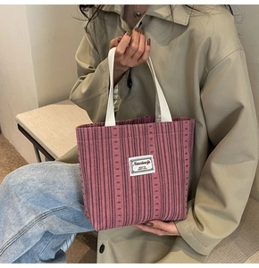 Close-up of retro striped corduroy tote bag with white woven logo and cotton handles