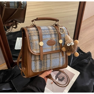 Details des britischen Plaid-Rucksacks mit Lederschnalle und Plüschmonster-Anhänger
