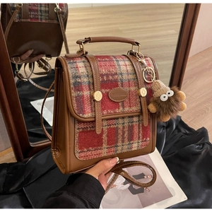 Detail der Vintage Plaid-Patchworktasche mit Plüsch-Anhänger und eleganter Metallplakette