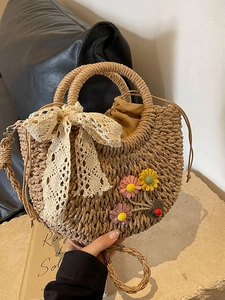 Handwoven straw basket bag with lace bow, floral accents and a circular handle