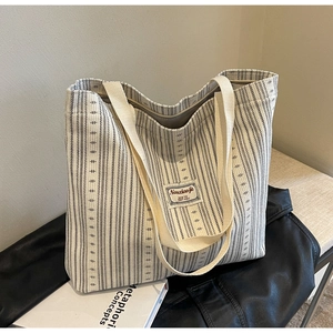 Detail shot of a large corduroy tote bag with black stripes on cream fabric material