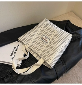 Detailed view of cream striped canvas tote bag with black patterns on leather jacket