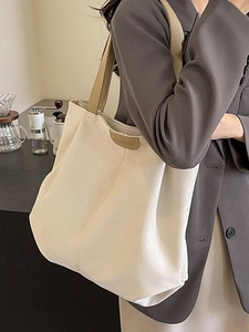 Minimalist canvas tote bag with brown straps shown in a stylish lifestyle setting