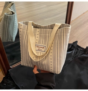 Close-up of black and white vertical striped canvas tote bag with Nanxiaojie logo patch