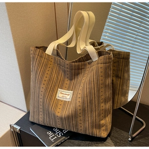 Detail of brown corduroy tote bag featuring striped texture and white canvas handles