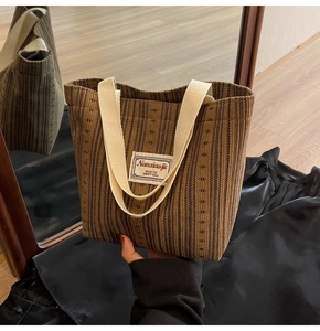 Close-up of brown striped texture on a knit tote bag with branded label and off-white straps