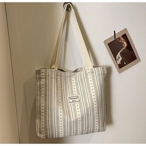 Detailed view of striped corduroy tote bag with fabric label and thick ribbon handles