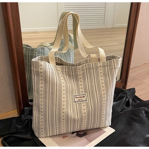 Detail of striped corduroy tote bag showing woven label and sturdy double handles