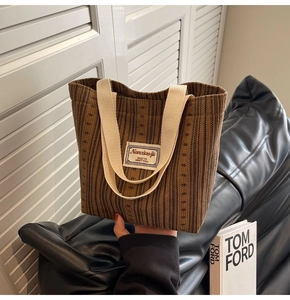 Detail of brown corduroy tote bag with ivory strap handles and woven brand patch