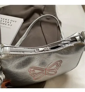 Detail eines glatten Metallreißverschlusses an einer silbernen Tasche mit Stickerei
