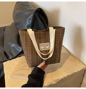 Detailed view of brown corduroy tote bag with vertical stripes and woven handles