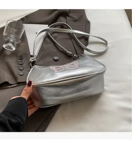 Details der silbernen Baguette-Tasche mit Knitteroptik und rosa Schmetterling-Stickerei