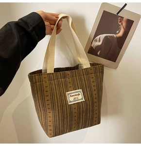 Macro detail of brown corduroy tote bag with white woven handles and Nanciaojie label