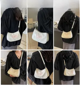 Detailaufnahmen der cremeweißen Lackleder-Baguette-Tasche mit rosa Schmetterlingsstickerei
