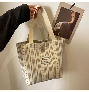 Detail of striped canvas tote bag with Nanxiaojie patch and woven top handles