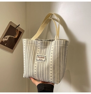 Detailed close-up of striped canvas tote bag showing the fine stitching and brand label