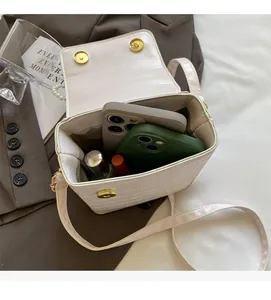 Detail view of white croc-embossed phone bag showing interior capacity for daily essentials