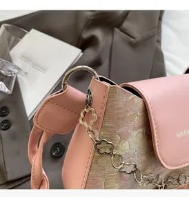 Détail du sac à bandoulière en jacquard rose avec boucle florale et texture logo