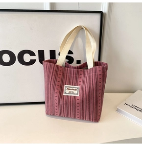 Detail of pink corduroy tote bag with woven handles and minimalist fabric label