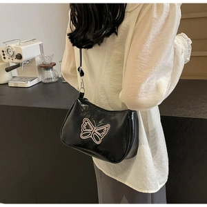 Detailansicht schwarze Baguette-Tasche mit rosa Schmetterlingsstickerei und Trageriemen