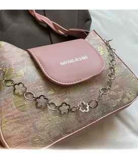 Détail du tissu jacquard floral rose et du rabat en cuir avec chaîne en métal à fleurs